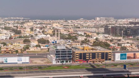 Téléchargez les photos : Vue aérienne vers Dubai City Walk district timelapse. Mosquée et circulation sur une autoroute. Nouvelle partie moderne avec des bâtiments de faible hauteur et des villas créées comme des rues de style européen. - en image libre de droit