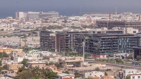 Foto de Vista aérea del timelapse del distrito Dubai City Walk. Nueva parte moderna con edificios de poca altura y villas creadas como calles de estilo europeo. Planta de construcción con grúas sobre fondo - Imagen libre de derechos