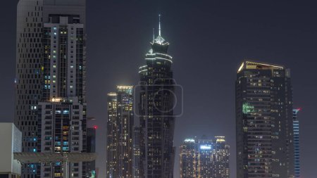 Foto de Skyline distrito de la bahía de negocios con la arquitectura moderna timelapse noche desde arriba. Vista aérea de los rascacielos y torres iluminadas de Dubái cerca de la carretera principal. Cielo oscuro - Imagen libre de derechos