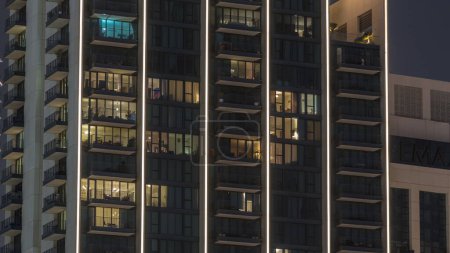 Foto de Grandes bloques de pisos con ventanas brillantes ubicados en el distrito residencial de la ciudad timelapse aéreo. Luz nocturna en las habitaciones en la parte superior de las torres y rascacielos - Imagen libre de derechos