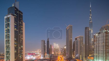 Foto de Vista aérea del horizonte del centro de Dubái con muchas de las torres más altas del día a la noche. Área de negocios en la ciudad urbana inteligente. Rascacielos y edificios de gran altura desde arriba después del atardecer, EAU. - Imagen libre de derechos