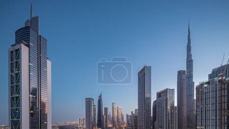Foto de Vista aérea del amanecer del horizonte del centro de Dubái con muchas torres de noche al día de transición timelapse. Área de negocios en la ciudad urbana inteligente. Rascacielos y edificios de gran altura desde arriba temprano en la mañana, Emiratos Árabes Unidos. - Imagen libre de derechos