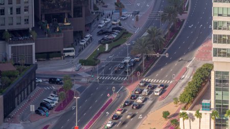 Foto de Vista aérea desde arriba a una concurrida intersección de carreteras en Dubai timelapse. Coloridos coches y camiones que conducen hacia adelante en ambas direcciones y peatones cruzando la carretera. Distrito financiero - Imagen libre de derechos