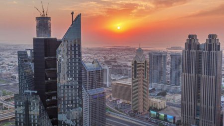 Foto de Edificios de gran altura en Sheikh Zayed Road en Dubai, Emiratos Árabes Unidos. Rascacielos en el distrito financiero internacional desde arriba durante la puesta del sol. Casas de paseo por la ciudad y villas en un fondo - Imagen libre de derechos