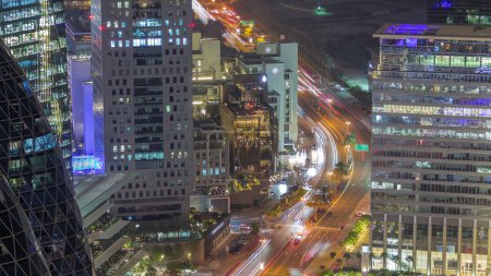 Foto de Vista aérea del tráfico en la calle Al Saada en el horario nocturno del distrito financiero en Dubai, Emiratos Árabes Unidos. Rascacielos iluminados y ventanas brillantes en torres de oficinas desde arriba. - Imagen libre de derechos