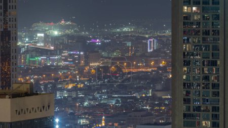 Foto de Vista aérea de casas de apartamentos y villas en la ciudad de Dubai cerca del timelapse del centro de la noche. Puerto marítimo sobre fondo. Emiratos Árabes Unidos - Imagen libre de derechos