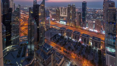Foto de Edificios de gran altura en Sheikh Zayed Road en Dubai antena día a noche transición panorámica timelapse, Emiratos Árabes Unidos. Rascacielos en el distrito financiero desde arriba. Casas de paseo por la ciudad y villas en un fondo - Imagen libre de derechos