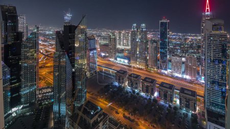 Téléchargez les photos : Bâtiments de grande hauteur sur Sheikh Zayed Road à Dubaï nuit aérienne timelapse panoramique, Émirats arabes unis. gratte-ciel dans le quartier financier international d'en haut. Maisons de promenade en ville et villas sur un fond - en image libre de droit