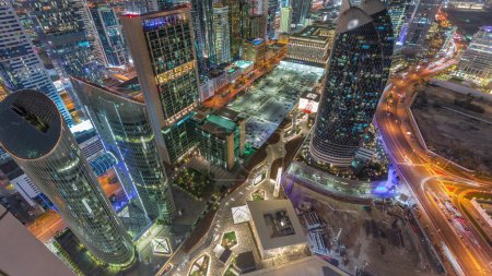 Téléchargez les photos : Skyline vue vers le bas des immeubles de grande hauteur sur Sheikh Zayed Road à Dubaï et parking aérien nuit timelapse, Émirats arabes unis. Des gratte-ciel éclairés de la place financière internationale d'en haut - en image libre de droit