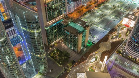 Téléchargez les photos : Skyline vue vers le bas des immeubles de grande hauteur sur Sheikh Zayed Road et un énorme parking à Dubaï timelapse de nuit aérienne, Émirats arabes unis. Des gratte-ciel éclairés de la place financière internationale d'en haut - en image libre de droit