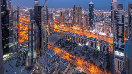 Téléchargez les photos : Bâtiments de grande hauteur sur Sheikh Zayed Road à Dubaï transition aérienne nuit au jour timelapse panoramique, EAU. Gratte-ciels dans le quartier financier d'en haut. Maisons de ville et villas en arrière-plan - en image libre de droit