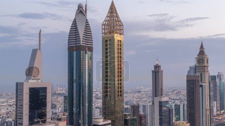 Foto de Vista del horizonte de los edificios de gran altura en Sheikh Zayed Road en Dubai noche aérea al día timelapse transición, Emiratos Árabes Unidos. Rascacielos en el Centro Financiero Internacional desde arriba antes del amanecer - Imagen libre de derechos