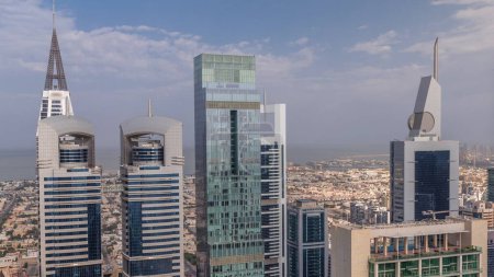 Foto de Vista del horizonte de los edificios de gran altura en Sheikh Zayed Road en Dubai timelapse aéreo, Emiratos Árabes Unidos. Rascacielos en el centro financiero del Centro Financiero Internacional desde arriba y casas de villas detrás de él - Imagen libre de derechos