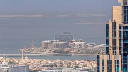 Foto de Vista aérea de casas de apartamentos y villas en la ciudad de Dubai cerca del timelapse del centro. Vista detrás de rascacielos con mezquita. Islas artificiales en un fondo. Emiratos Árabes Unidos - Imagen libre de derechos