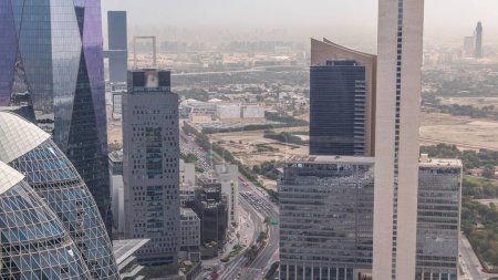 Foto de Vista del horizonte de los edificios de gran altura alrededor del tráfico en la carretera en Dubai timelapse aéreo, Emiratos Árabes Unidos. Rascacielos en el centro financiero del Centro Financiero Internacional desde arriba. Deira distrito en el fondo - Imagen libre de derechos