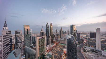 Foto de Vista panorámica del horizonte de los edificios de gran altura en Sheikh Zayed Road en Dubai noche aérea al día timelapse transición, Emiratos Árabes Unidos. Rascacielos en el Centro Financiero Internacional desde arriba antes del amanecer - Imagen libre de derechos