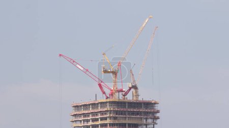 Foto de Muchas grúas torre que trabajan en el sitio de construcción del nuevo rascacielos del edificio de gran altura comercial monolítico timelapse aéreo. Avanzar en Dubai centro - Imagen libre de derechos