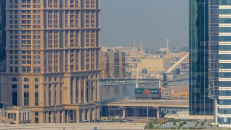 Téléchargez les photos : Promenade à pied le long du canal d'eau dans le quartier Business Bay de Dubaï timelapse aérien. Villas et mosquée derrière. Ponts au-dessus du front de mer avec gratte-ciel d'en haut, Émirats arabes unis - en image libre de droit