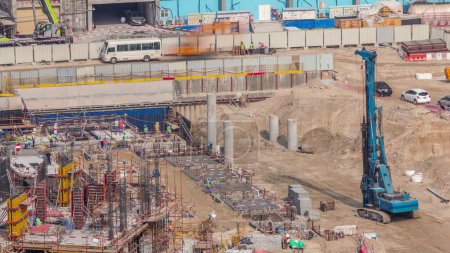 Foto de Gran obra de construcción con muchas grúas de trabajo timelapse. Vista aérea superior de gran desarrollo del distrito residencial y de oficinas en Business Bay, Dubai. Fosa de excavación con pilotes - Imagen libre de derechos