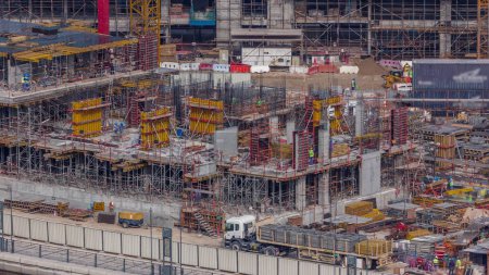 Foto de Gran obra de construcción con muchas grúas de trabajo timelapse. Vista aérea superior de gran desarrollo del distrito residencial y de oficinas en Business Bay, Dubai. Bulldozer y camión - Imagen libre de derechos
