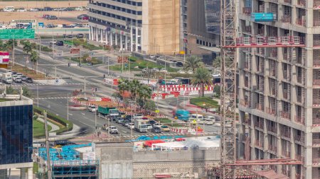 Photo for Large construction site with many working cranes timelapse. Traffic on the intersection. Top aerial view of big development of residential and office district in Business bay, Dubai - Royalty Free Image