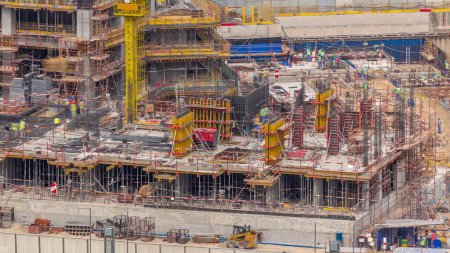Photo for Large construction site with working cranes timelapse. Top aerial close up view of big development of residential and office district with many workers in Business bay, Dubai - Royalty Free Image