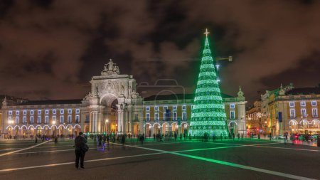 Téléchargez les photos : Commerce square illuminated and decorated at Christmas time in Lisbon night timelapse hyperlapse. Commercio square with christmas tree and people tourists crowd around, city of europe - en image libre de droit
