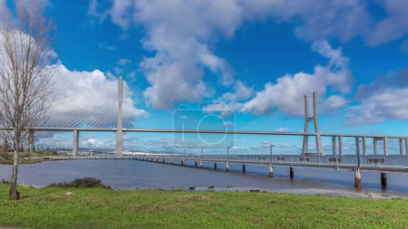 Téléchargez les photos : The Vasco da Gama Bridge timelapse hyperlapse with pier. Cable-stayed longest bridge flanked by viaducts and rangeviews that spans the Tagus River in Park of Nations in Lisbon, Portugal - en image libre de droit