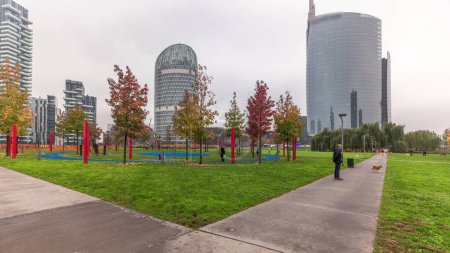 Foto de Panorama mostrando rascacielos y biblioteca del parque con césped verde y naranjos timelapse. Situado entre Piazza Gae Aulenti y el distrito de Isola. Tráfico en una intersección de carreteras. Milán. Italia - Imagen libre de derechos
