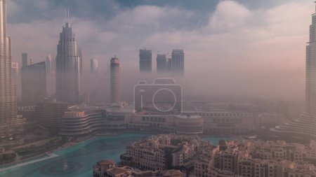 Téléchargez les photos : Vue aérienne matin brouillard couvert Dubaï International Financial Centre quartier timelapse. Tours de bureaux et hôtels avec gratte-ciel et centre commercial modernes au lever du soleil - en image libre de droit