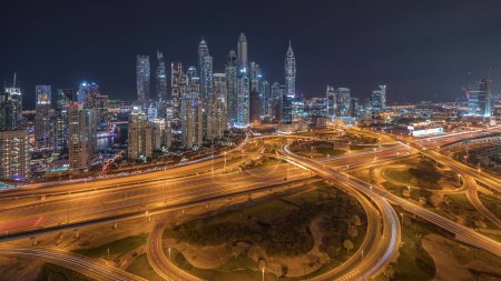 Foto de Panorama de Dubai Marina mostrando cruce de carretera espagueti cruce noche timelapse. Rascacielos más altos iluminados sobre un fondo. Vista aérea desde el distrito JLT. - Imagen libre de derechos