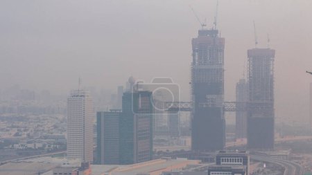 Téléchargez les photos : Vue aérienne des gratte-ciel éclairés avec World Trade Center à Dubaï timelapse avant le lever du soleil. Site de construction de nouvelles tours jumelles. Bur Dubai et le district de Deira sur un fond - en image libre de droit