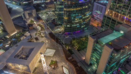Téléchargez les photos : Dubaï gratte-ciel de centre financier international et promenade sur une avenue porte aérienne de jour à nuit passage timelapse. Les tours éclairées et la mosquée regardent vers le bas vue d'en haut - en image libre de droit