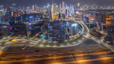 Téléchargez les photos : Panorama montrant l'horizon de Dubaï avec la baie d'affaires et le quartier du centre-ville timelapse de nuit. Vue aérienne de nombreux gratte-ciel modernes et la circulation achalandée sur la route al khail. Émirats arabes unis. - en image libre de droit