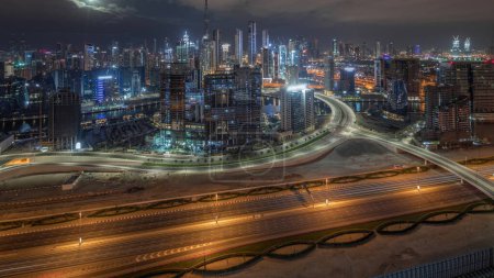 Foto de Skyline panorámico de Dubai con bahía de negocios con el distrito financiero y el centro durante toda la noche. Vista aérea de muchos rascacielos modernos y tráfico ocupado en la carretera al khail. Emiratos Árabes Unidos. - Imagen libre de derechos