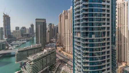 Téléchargez les photos : Panorama montrant vue aérienne sur les gratte-ciel de la marina de Dubaï autour du canal avec des bateaux flottants et jlt avec jbr districts timelapse. Les bateaux blancs sont garés dans le yacht club - en image libre de droit