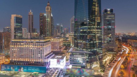 Foto de Dubai International Distrito financiero día a noche timelapse transición. Vista aérea de las torres de oficinas de negocios después del atardecer. Rascacielos con hoteles y centros comerciales cerca del centro - Imagen libre de derechos