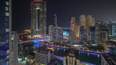 Photo for Panorama showing Dubai Marina with several boat and yachts parked in harbor and illuminated skyscrapers around canal aerial night timelapse. Towers of JBR district on a background - Royalty Free Image