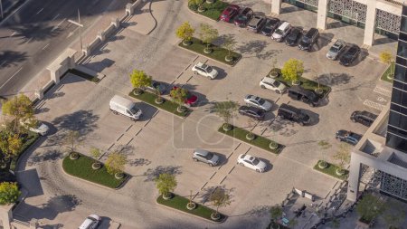 Photo for Car parking lot viewed from above timelapse during all day, Aerial view. Top view of vehicles parked near office building in Dubai. Shadows moving fast - Royalty Free Image