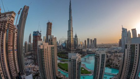 Photo for Panorama of Dubai Downtown cityscape with tallest skyscrapers around aerial night to day transition timelapse. Construction site of new towers and busy roads with traffic from above - Royalty Free Image