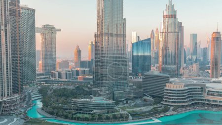 Téléchargez les photos : Gratte-ciel s'élevant au-dessus du centre-ville de Dubaï, centre commercial et fontaine entourés de bâtiments modernes vue panoramique aérienne avec ciel nuageux au coucher du soleil - en image libre de droit