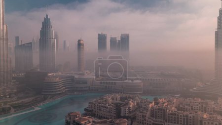 Photo for Aerial view morning fog covered Dubai International Financial Centre district. Office towers and hotels with modern skyscrapers and mall during sunrise - Royalty Free Image