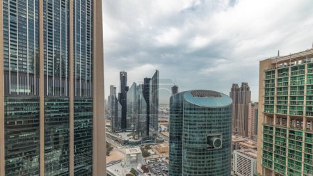 Foto de Panorama que muestra los rascacielos del centro financiero internacional de Dubai con paseo marítimo en una antena de la avenida de la puerta. Muchas torres de oficinas y el tráfico en una carretera. Cielo nublado - Imagen libre de derechos