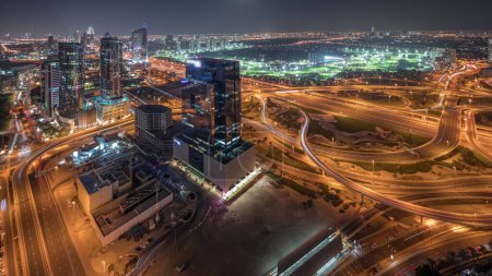 Téléchargez les photos : Panorama montrant la marina de Dubaï et les gratte-ciel illuminés par JLT le long de Sheikh Zayed Road avec une énorme jonction et une nuit aérienne de quartier médiatique. Immeubles résidentiels et de bureaux d'en haut. - en image libre de droit