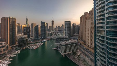 Téléchargez les photos : Vue aérienne des gratte-ciel de la marina de Dubaï autour du canal avec des bateaux flottants toute la journée. Les bateaux blancs sont garés dans un yacht club. Ombres se déplaçant rapidement - en image libre de droit