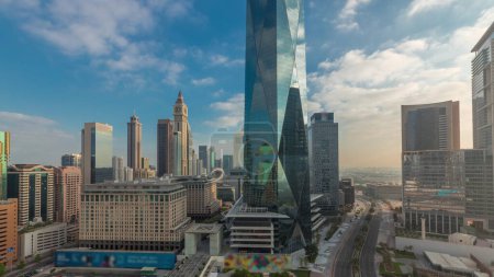 Foto de Salida del sol en el distrito financiero internacional de Dubai transición. Vista aérea panorámica de las torres de oficinas de negocios por la mañana. Rascacielos con hoteles y centros comerciales cerca del centro - Imagen libre de derechos