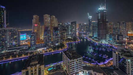 Téléchargez les photos : Panorama montrant les gratte-ciel de Dubai Marina et le quartier JBR avec des bâtiments de luxe et des stations balnéaires. Bord de l'eau éclairé et bateaux flottant dans le canal - en image libre de droit