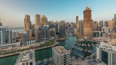 Téléchargez les photos : Panorama montrant les gratte-ciel de Dubai Marina et le quartier JBR avec des bâtiments de luxe et des stations aériennes. Bord de l'eau avec palmiers et bateaux flottant dans le canal - en image libre de droit