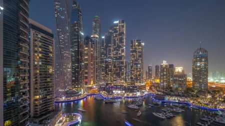 Photo for Dubai marina tallest skyscrapers and yachts in harbor aerial night panoramic after sunset. View at apartment buildings, hotels and office blocks, modern residential development of UAE - Royalty Free Image