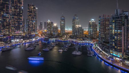 Foto de Bahía de yates de lujo en la ciudad día aéreo a la transición nocturna en Dubai marina. Rascacielos modernos a lo largo del paseo marítimo y barcos flotando en el puerto - Imagen libre de derechos